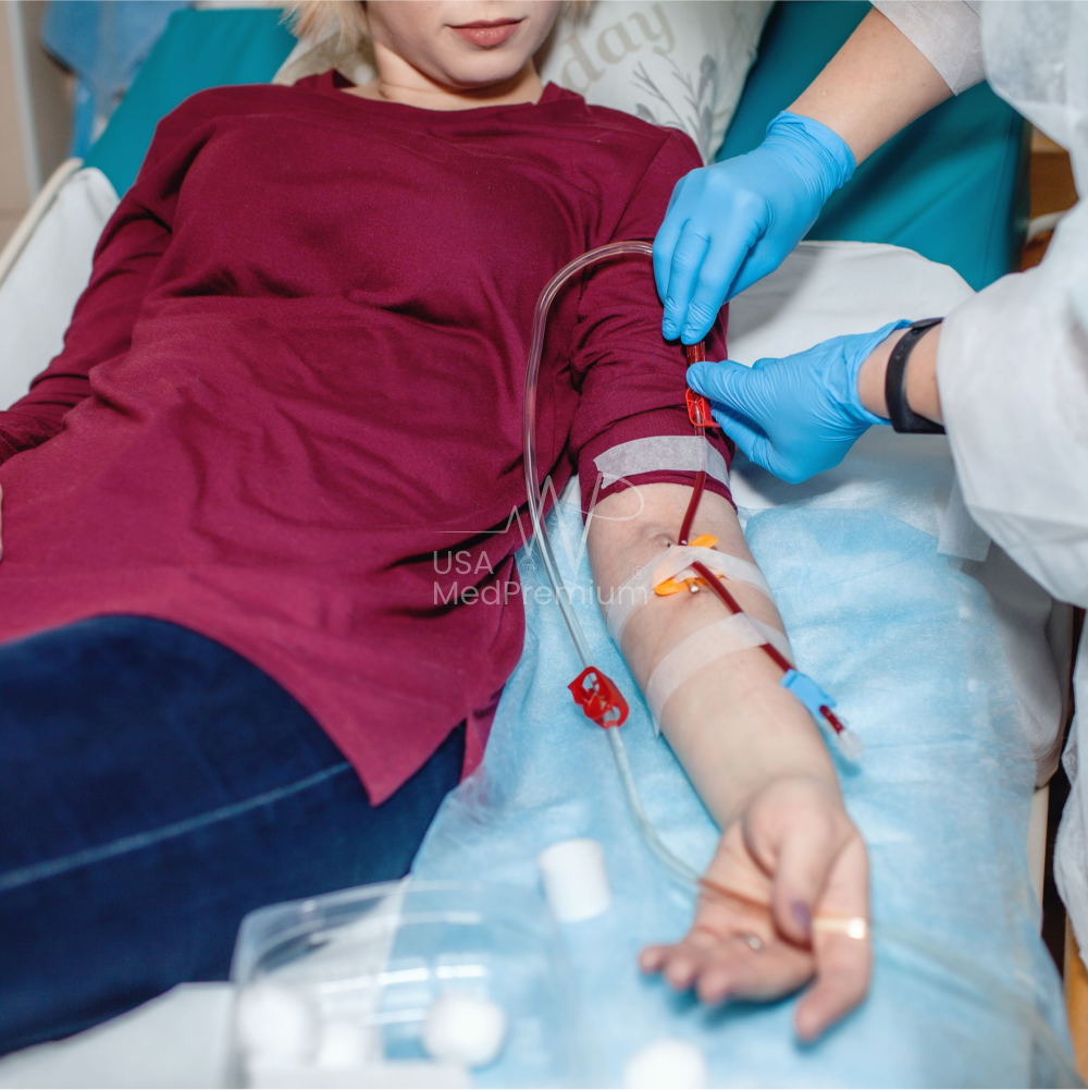 Dialysis nurse adjusting a hemodialysis machine beside a seated patient in a treatment chair