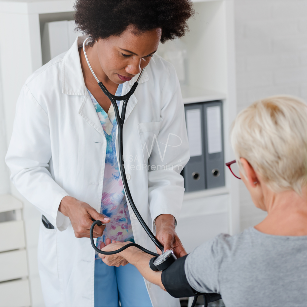 Physician listening to a patient with a stethoscope in a stocked exam room with wall-mounted diagnostic instruments